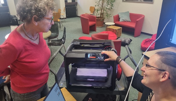 Die Porzer Stadtbibliothek bietet regelmäßig einen Workshop für 3-D-Druck an. Die Kursleiterin Yvonne Fischer erklärt Kursteilnehmerin Heinke Groll, wie das Gerät funktioniert. Foto: Lars Germann